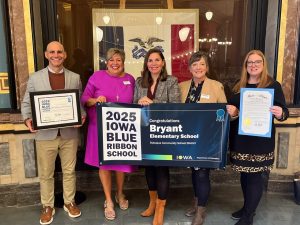 Bryant Elementary School staff posing at the Iowa Capitol a banner, certificate and proclamation honoring Bryant as an Iowa Blue Ribbon School.